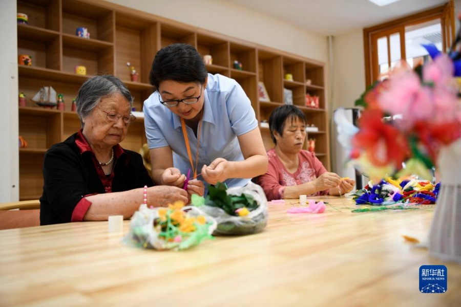 2023年8月27日、河北省承德市双滦区のある介護サービスセンターでスタッフのサポートを受けながら工作をする高齢者女性（撮影・王立群）。