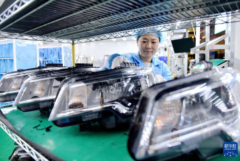 阜城県にある自動車部品メーカーの工場で、自動車のヘッドライトを棚に並べる作業員（3月25日撮影・王暁）。