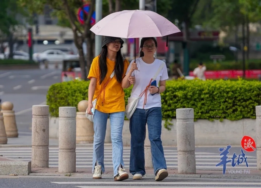 3月25日、Tシャツ姿で日傘をさして街を歩く広州の女性（撮影・梁懌韜）。