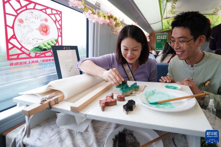 民間アーティストに教えてもらいながらカラフルな花の版画「餖彩拱花」を制作する乗客（写真左、4月2日撮影・李博）。
