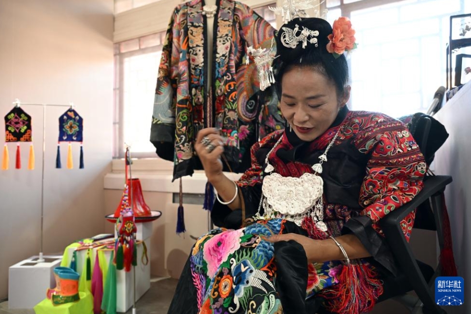 作品展の会場で刺繍技術を披露する貴州省から来た女性障がい者の刺繍家・張艷梅さん（5月12日撮影・金良快）。