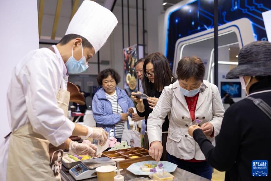 「中華老字号」の認証を受けた老舗の「喬家柵」の展示ブースで、会場で作られた菓子を試食する来場者（5月13日撮影・王翔）。