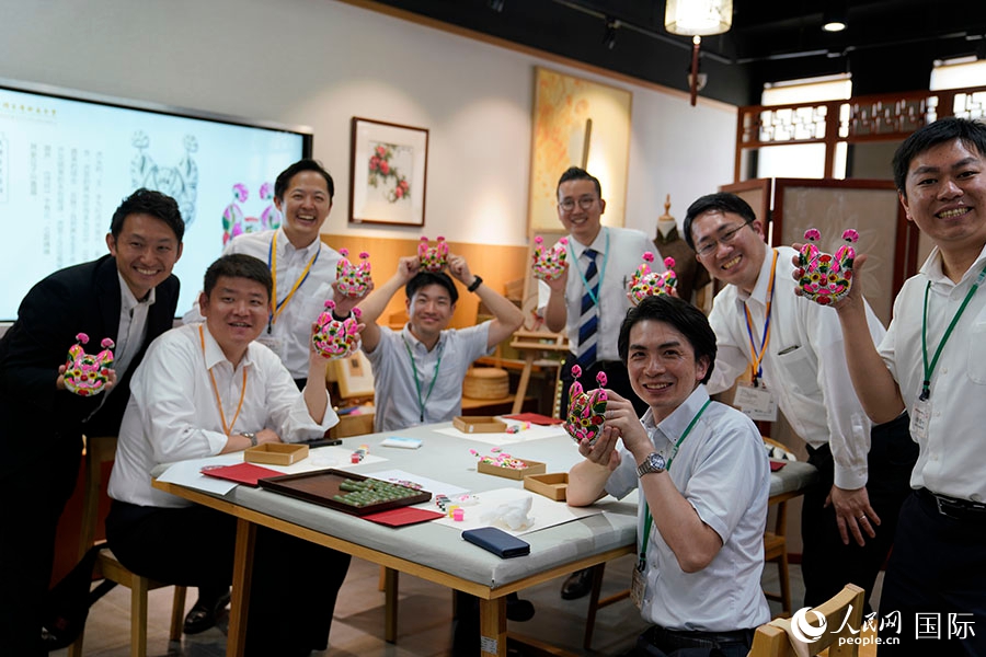 自分で色付けした泥人形を見せる日本の創価学会青年代表団メンバー（撮影・張麗婭）。