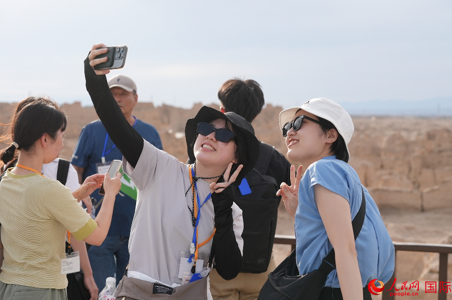 「交河故城」で記念写真を撮影する創価学会青年代表団のメンバー (撮影・張麗婭) 。