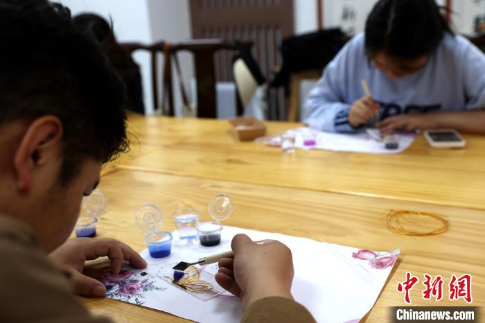 青海省西寧市の青年夜間スクールの教室で、無形文化遺産の魅力を感じながら、掐絲琺瑯の制作法を学ぶ受講生たち（6月13日撮影・薛蒂）。