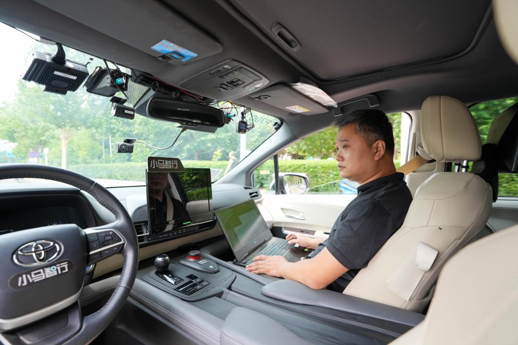 道路を走る自動運転テスト車両内で車載機器の路上試験をする王偉さん（6月19日撮影）。