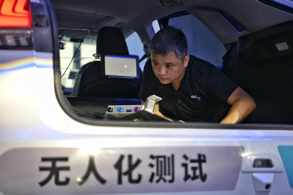 自動運転テスト車両の車内に搭載されている設備を検査する王偉さん（6月19日撮影）。