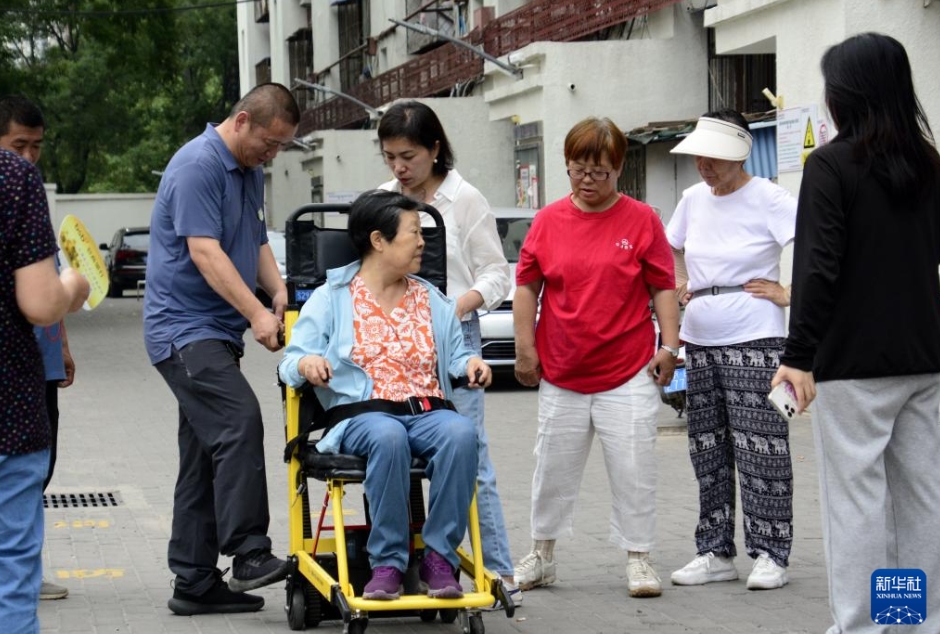 北京市朝陽区青年路社区にある古い社区で、「可搬型階段昇降機」の使い方を学ぶ住民（7月11日撮影・李欣）。