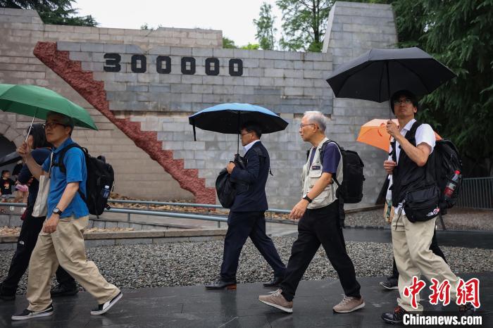 雨の中、中国侵略日本軍南京大虐殺遇難同胞紀念館を見学する「平和の旅　訪中団」のメンバー（撮影・泱波）。
