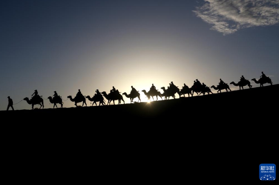 甘粛省敦煌市の鳴沙山月牙泉景勝地をラクダの背に乗り、観光する人々(7月14日撮影・張暁亮）。