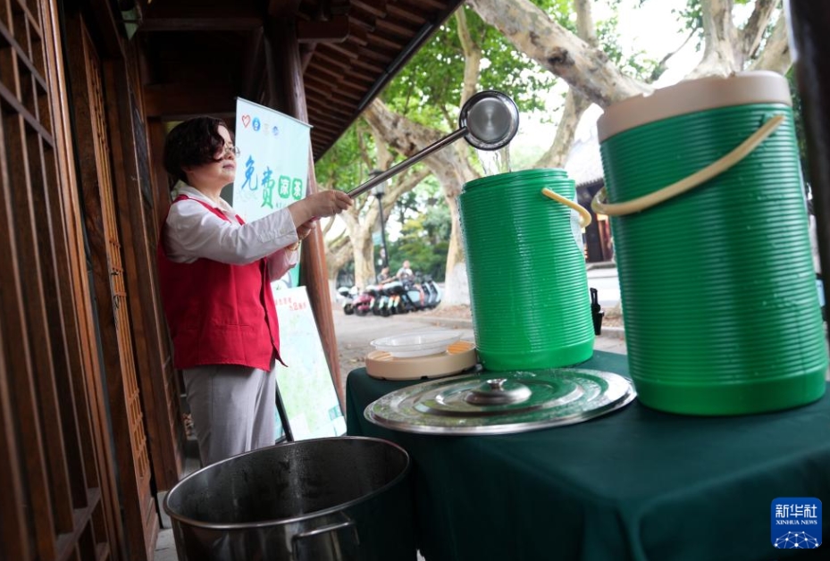 杭州西湖景勝地の「西子驛・平湖秋月」にある「涼茶」無料提供スポットで、「涼茶」のディスペンサーに水を補充するボランティア（7月15日撮影・韓伝号）。