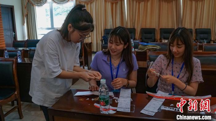 日本の若者たちにゴム動力飛行機の作り方を教える桂林航天工業学院の学生（写真左、7月22日撮影・蒋豊慧）。