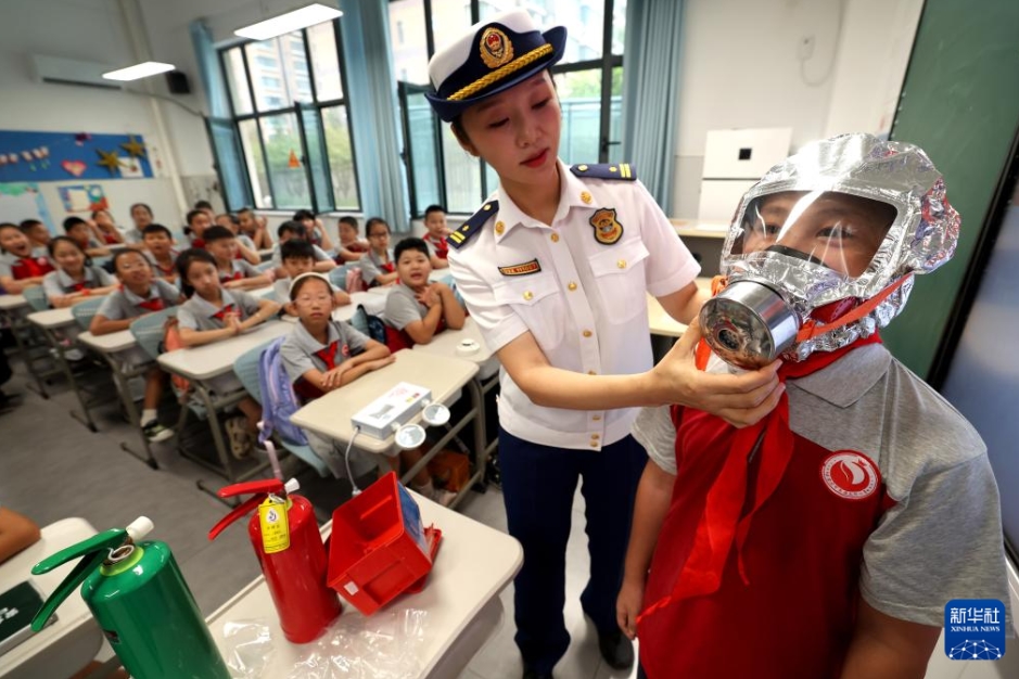 河北省石家荘市にある友誼大街小学校の新学期最初の授業で、防火マスクの使い方を児童に説明する消防士（9月1日撮影・梁子棟）。