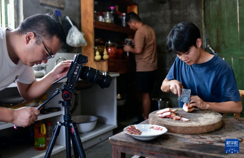 陳家寨村で、臘肉（燻製豚肉）を宣伝するショート動画を撮影する「念郷人周周」撮影チームのメンバー（9月26日撮影・楊文斌）。