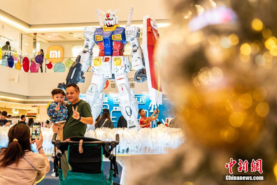 高さ3メートルの初代ガンダムRX-78-2の立像の前で記念撮影する市民や観光客（撮影・侯宇）。