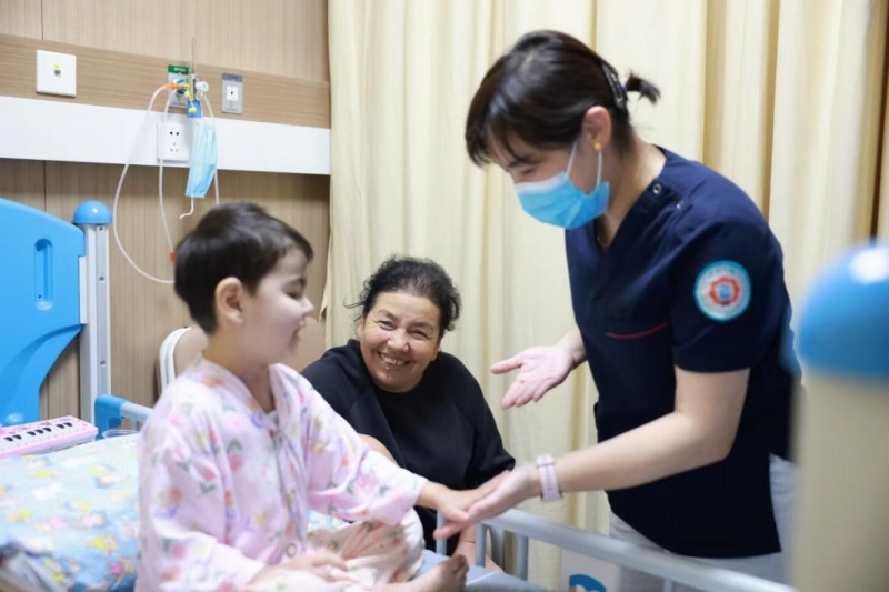 病室で診察を受ける艾力西木ちゃんと母親（写真中央）、単看護師長（写真右、画像提供・浙江大学医学院附属児童病院）。