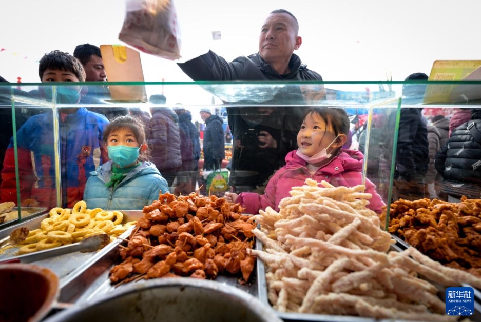 金貴定期市場で軽食を買う人（1月21日撮影・馮開華）。