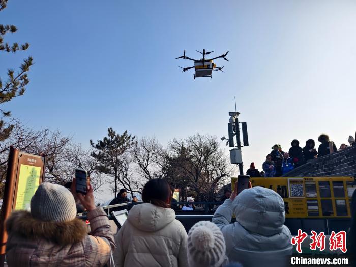 今年の春節期間中に、北京八達嶺長城の南五楼露台付近に飛んできたドローンをスマホで撮影する観光客（撮影・李夢）。