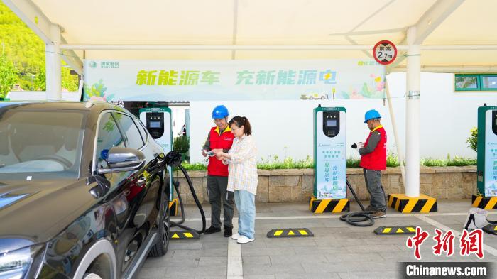 湖州市安吉県余村景勝地の「グリーン充電スタンド」で電気保安点検を行う作業員。撮影・董振茂