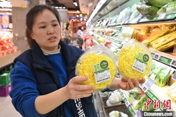 長沙市にあるスーパーで、食用の菊の花を見せる店員（3月12日撮影・楊華峰）。