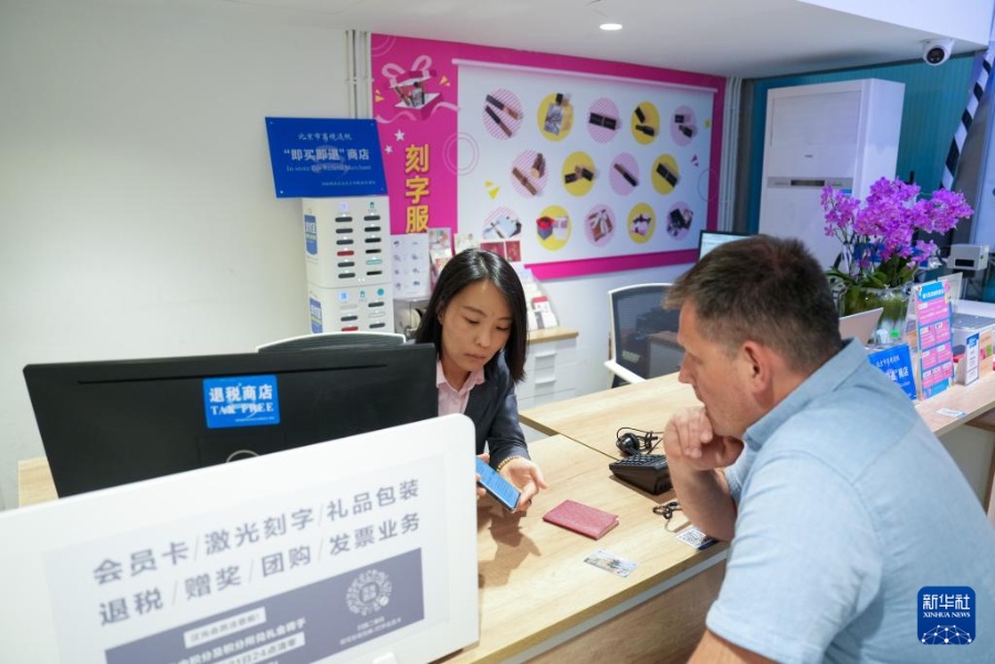 4月30日、北京市のデパート・漢光百貨の税還付カウンターでロシアからの観光客のために出国時の「免税額即時還付サービス」の手続きを行う担当者（左）（撮影・鞠煥宗）。