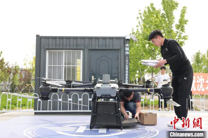ドローンが配送ステーションの離着陸地点に無事着陸し、貨物受取人の学生に引き渡す準備を行う順豊速運のスタッフ。（写真提供：輝山経済技術開発区）