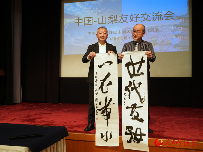 写真：「一衣帯水」「世代友好」と揮毫した作品を手にする両国の書道家。（撮影・許可）