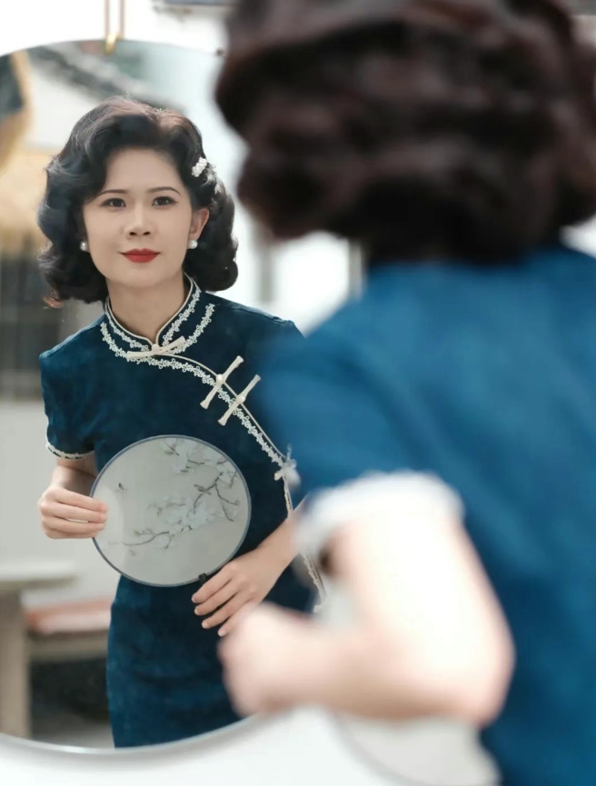 「手巻きカールヘア」の仕上がりを鏡でチェックする女性。