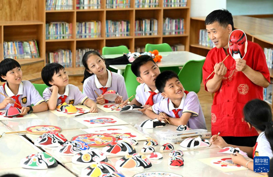石家荘市裕華西路小学校で児童たちに、京劇の臉譜の絵付けを紹介する張建認さん（6月10日撮影・陳其保）。