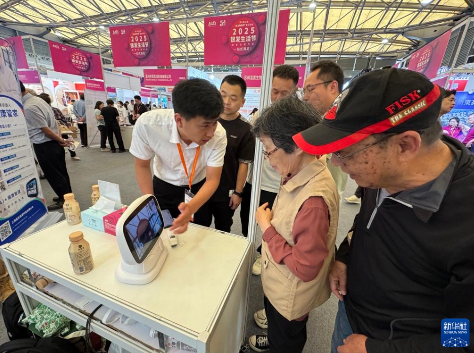 老博会会場で、出展企業からヘルスケア管理ロボットについて説明を受ける来場者（6月11日撮影・黄安琪）。