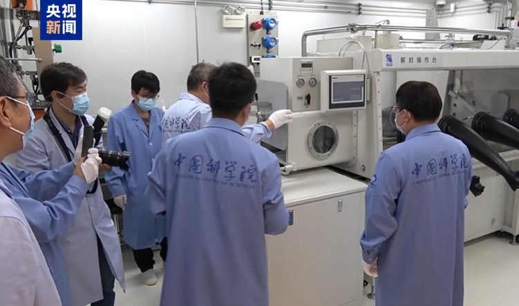 サンプルの密封装置を開封作業台に移す研究チーム
