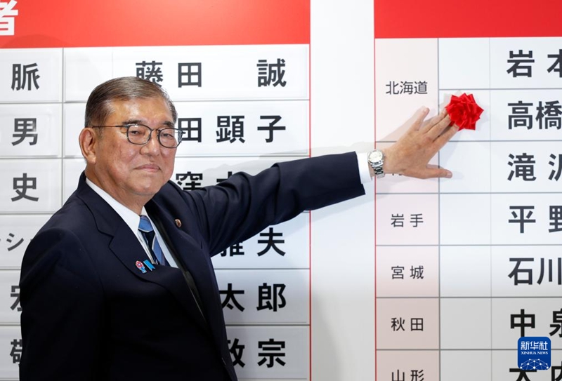 東京の自民党本部で20日、当選した議員の名前の上に花を添える石破茂首相。