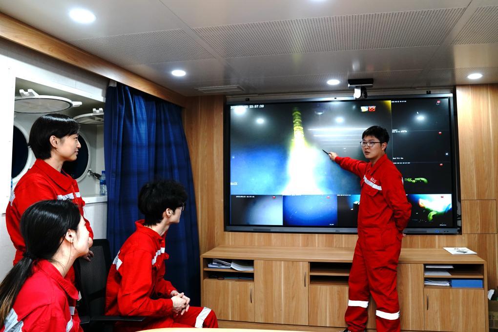 8月22日夜、中山大学号の科学調査センターで、海琴号が深海から送信する「ライブ映像」を見ながら議論している調査隊員たち。撮影・張建松