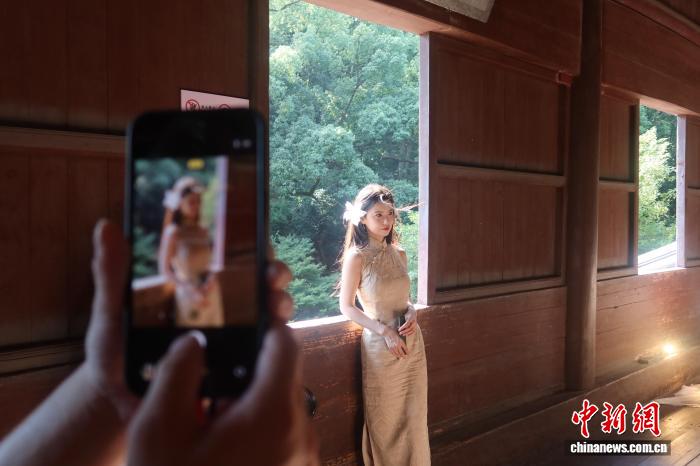 六和塔の木製の窓をバックに写真を撮影する女性（8月30日撮影・孫琳茹）。