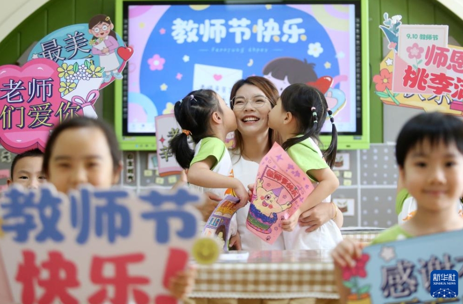 江蘇省揚州大学附属西郡幼稚園で、先生の頬にキスする園児（9月10日撮影・孟徳龍）。