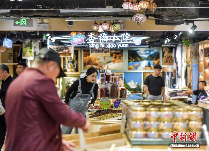 新疆維吾爾自治区烏魯木斉（ウルムチ）市の大バザール歩行街で、果物市場でドライフルーツを選ぶ観光客（9月22日撮影・劉新）。