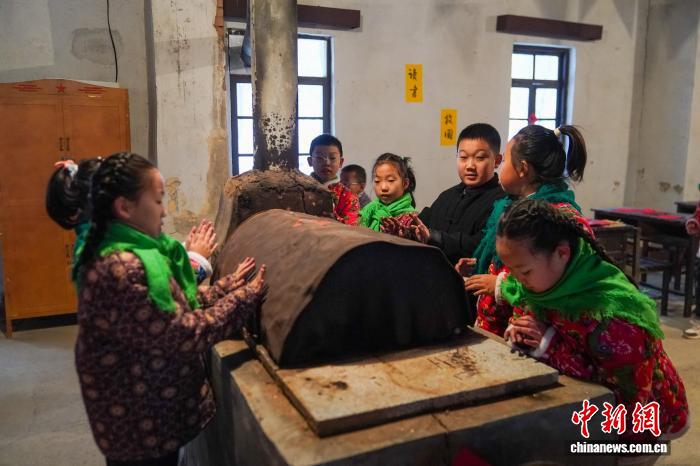 黒竜江省鉄力市の透竜景勝地で、ストーブの傍で火にあたる子供（11月29日撮影・趙宇航）。