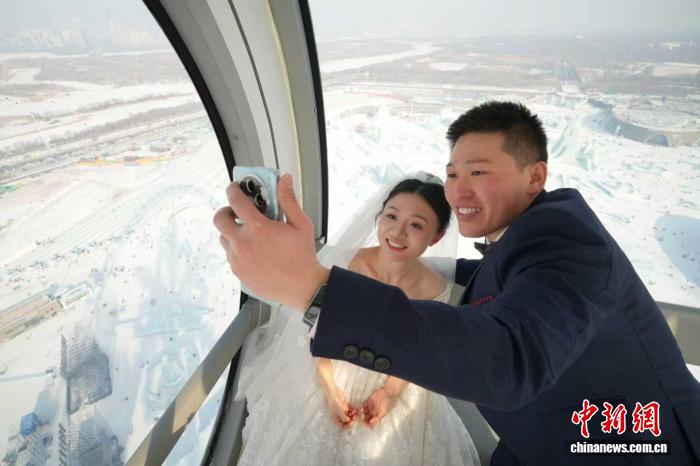 哈爾浜氷雪大世界の観覧車の中で写真を撮影する新郎新婦（撮影・于琨）。