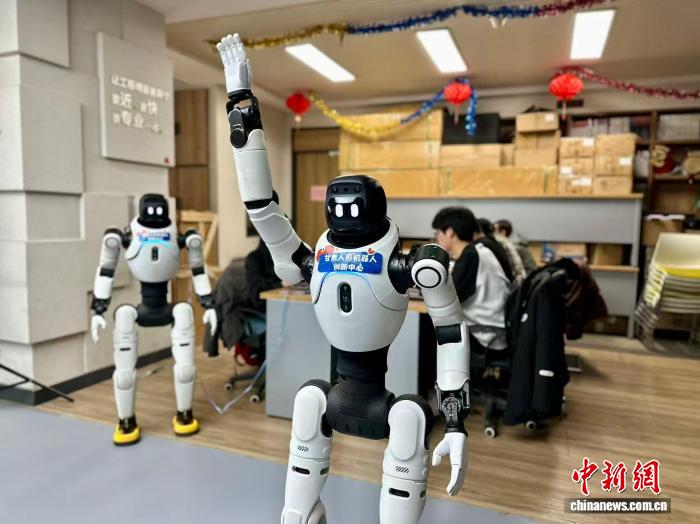 甘粛省蘭州市城関区において、人型ロボットに指定のアクションをさせるロボット訓練士ら（3月13日撮影・閆姣）。