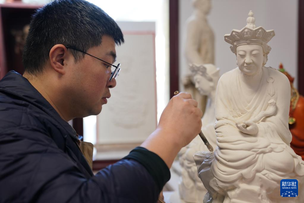 「無語仏」のレプリカに彩色を施す曾鋭さん（3月12日撮影）。