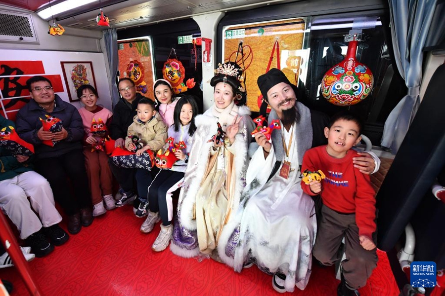 西安市内を走る観光バスの車内で、李白や楊貴妃に扮したスタッフと記念写真を撮影する観光客（2025年1月30日撮影）。
