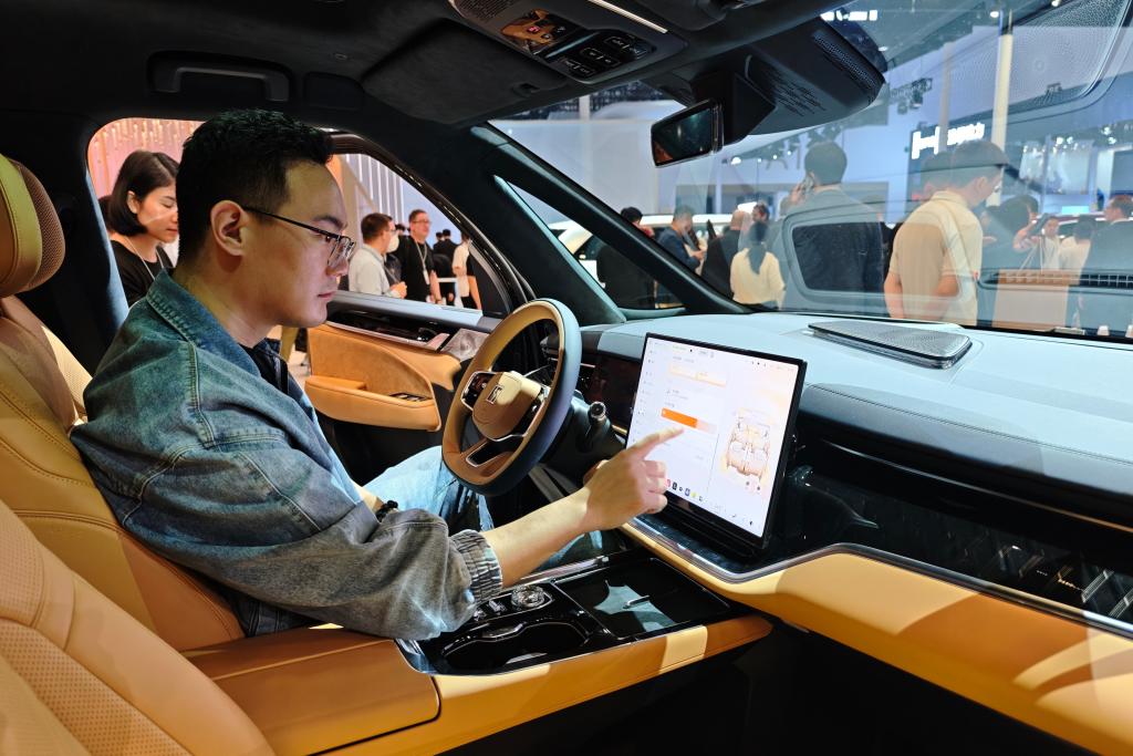 2026北京モーターショーの極氪(ZEEKR)の展示エリアで、新エネ車のスマート機能を体験する男性(撮影・唐詩凝)。