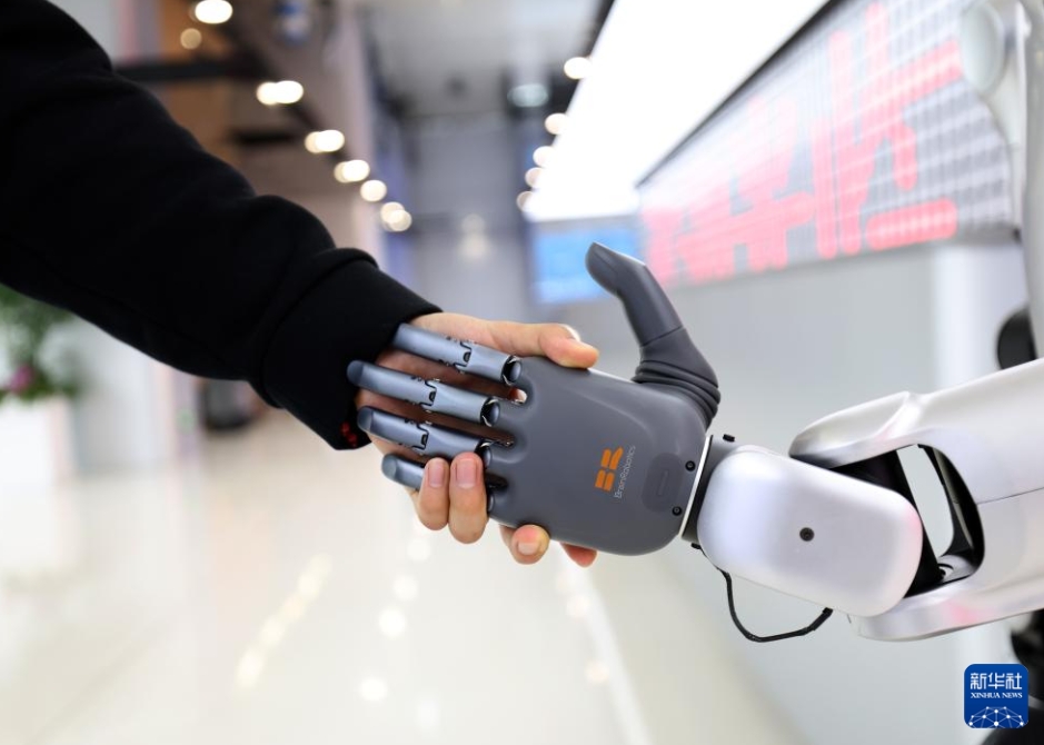 中原異種構造人型ロボット「4S店」で、店員が人型ロボットと握手する様子（5月6日撮影・李嘉南）。