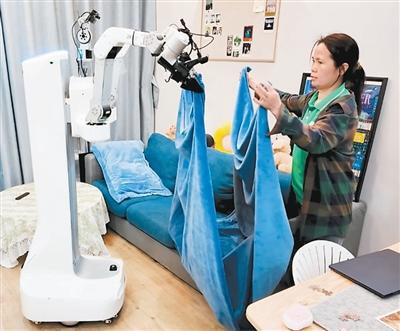 広東省深セン市南山区では、家事代行スタッフとロボットが協力してシーツを畳んでいる。撮影・周倩