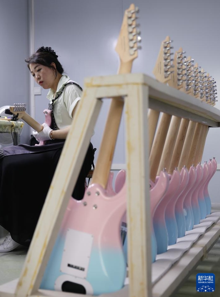湖南省永州市東安県のギター産業パークで、エレキギターのチューニングを行う作業員（5月12日撮影・趙仲志）。