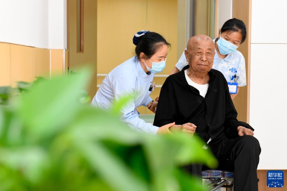 菏沢市の介護施設「鄆城唐塔養老アパートメント」で、部屋に戻る長期介護保険利用者の男性の車椅子を押すスタッフ（5月17日撮影・郭緒雷）。