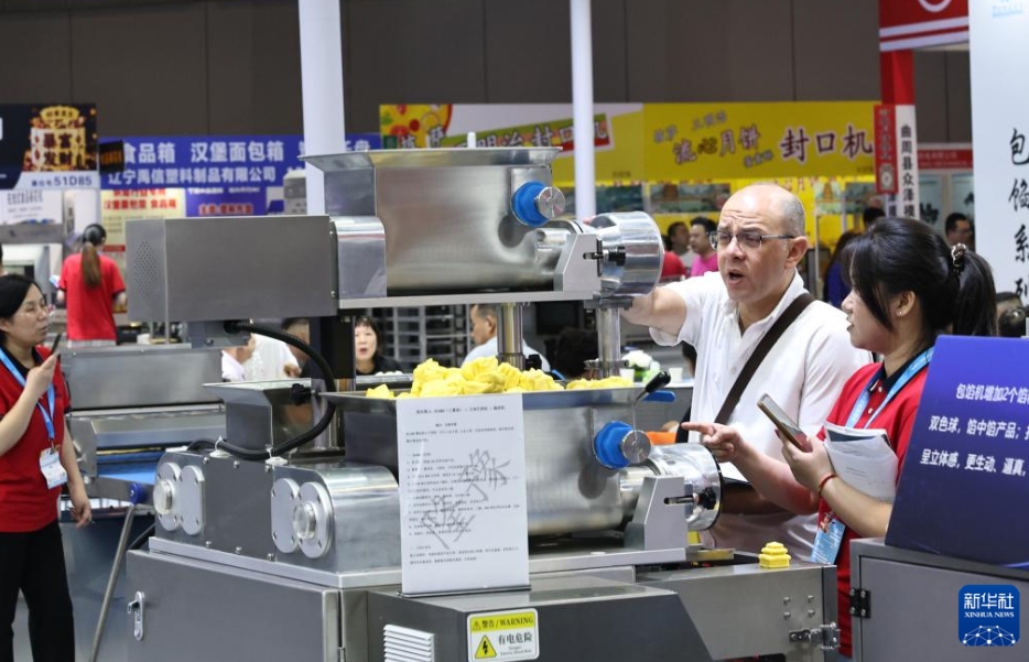 自動包餡機の展示品の前で、スタッフに質問する外国人ビジネスマン（5月20日撮影・方喆）。