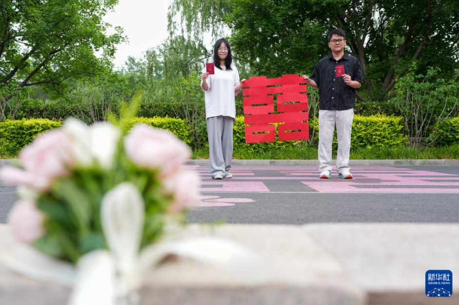 北京市東城区の玉蜓公園にある東城区婚姻届提出機関の外で、記念写真を撮影する、結婚証を受け取ったばかりのカップル（5月20日撮影・鞠煥宗）。