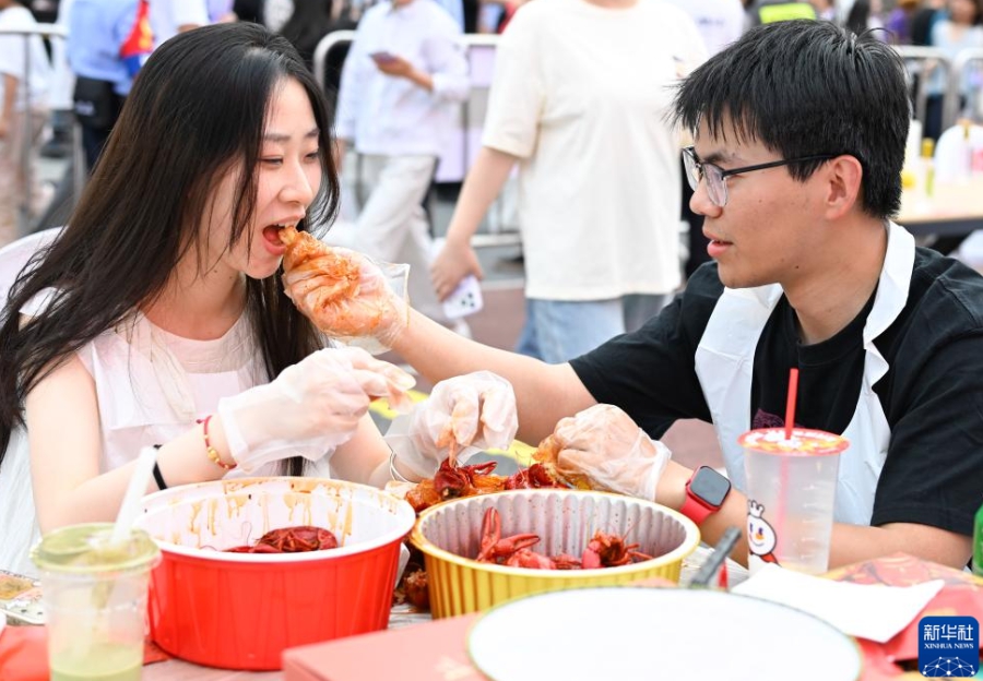 盱眙ザリガニフェスティバルの広場でザリガニを味わう江蘇省南京市から訪れたカップル（6月12日撮影・季春鵬）。