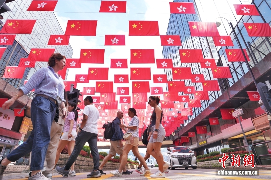 国旗と特区区旗が一面に掲げられた通りを行き交う歩行者（撮影・張祥毅）。